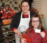 KONICA MINOLTA DIGITAL CAMERA Emily Bradshaw and Amy Lear, owner of Man in the Moon Candies, display the winning raffle ticket. Liz Cannady won the dozen chocolate roses. Emily raised $174 with the raffle.
