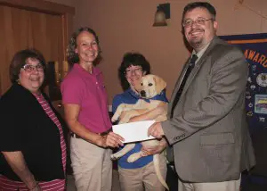 The Fulton Lions Club presented a donation to Guiding Eyes For The Blind in remembrance of Past President Donald “Charby” Charbonneau, who passed away earlier this year, at their Sept. 17 meeting. Past President David Guyer presents the donation to Cynthia Swift, Guiding Eyes trainer. Joining them are, from left: Patti Charbonneau, Donald’s wife; Mary Oonk, Guiding Eyes trainer; and Kimberly, a 13-week-old Yellow Labrador Retriever in training. The Fulton Lions have sponsored a Guiding Eyes Labrador Retriever named Charby, and also renamed their annual duck derby, Charby’s Duck Derby, in honor of Charbonneau who created the event 25 years ago. 