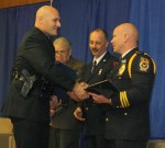 Officer Lucas Hollenbeck accepts the Police Officer of  the Year award from Police Chief Orlo Green, as Acting Fire Chief William Molascon and Mayor Ron Woodward look on.