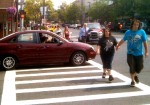 A car stopped in crosswalk as pedestrian signal show 18 seconds of crossing time for pedestrians still available. Vehicles driving into the crosswalk when pedestrians are crossing is a ticketable offense acccording to New York State Traffic Safety Regulations.